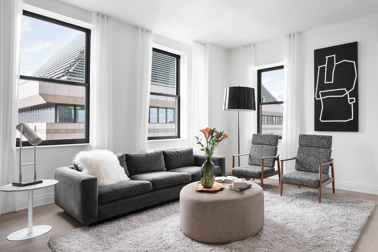 A living room with two large windows and a gray couch.